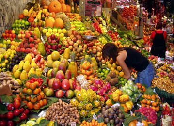 a woman picking up fruit at a market