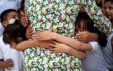 a woman in a floral dress hugging another woman