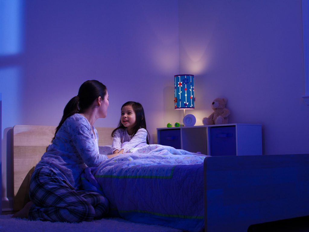 a woman and a little girl sitting on a bed