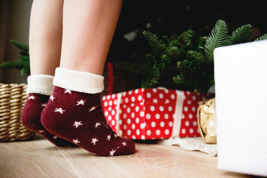 a woman's legs in red and white socks next to presents