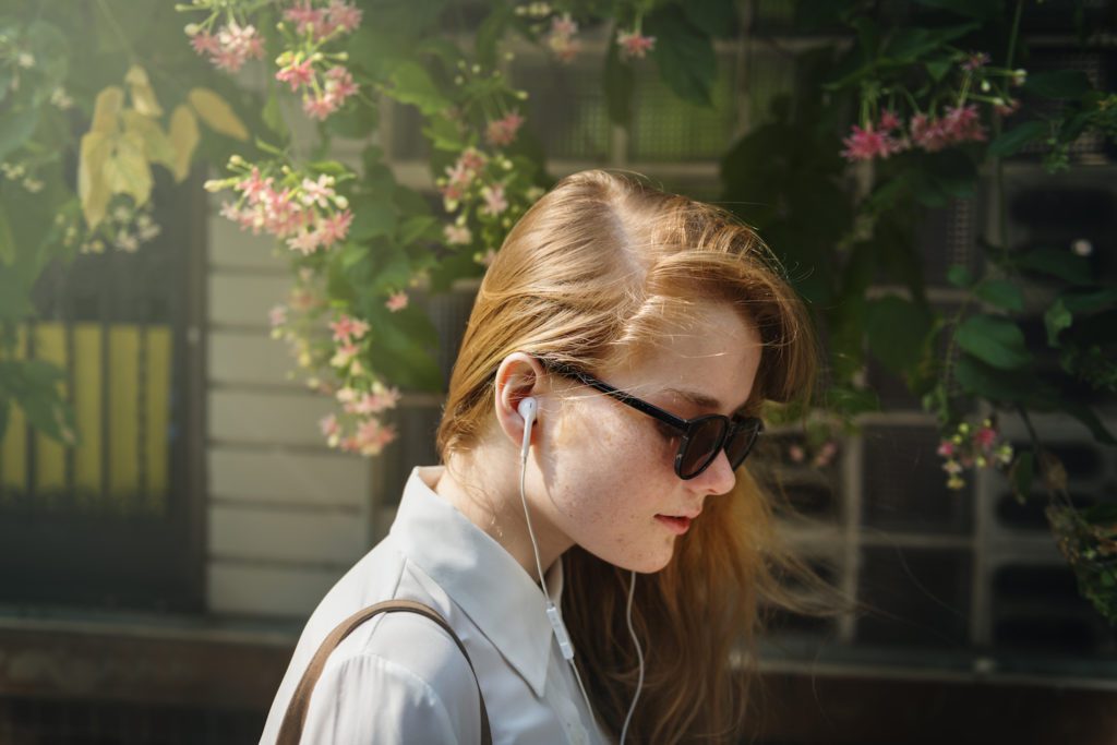 a woman with sunglasses and headphones is looking at her cell phone