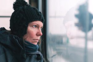 a woman wearing a black hat looking out the window