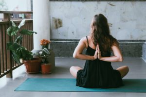 a woman sitting on a yoga mat in front of a potted plant