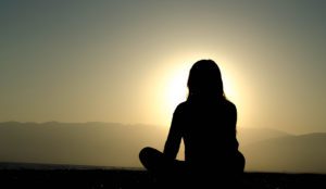 a person sitting on the ground in front of the sun