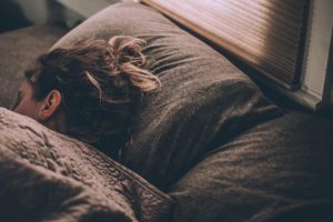 a woman laying on top of a couch under a blanket