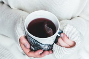 a woman holding a cup of tea in her hands