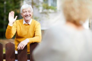 an older man is sitting on a bench and waving