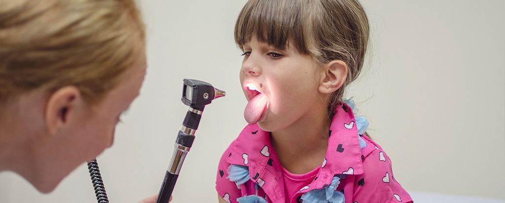 a little girl with her tongue out and an electric toothbrush in her mouth