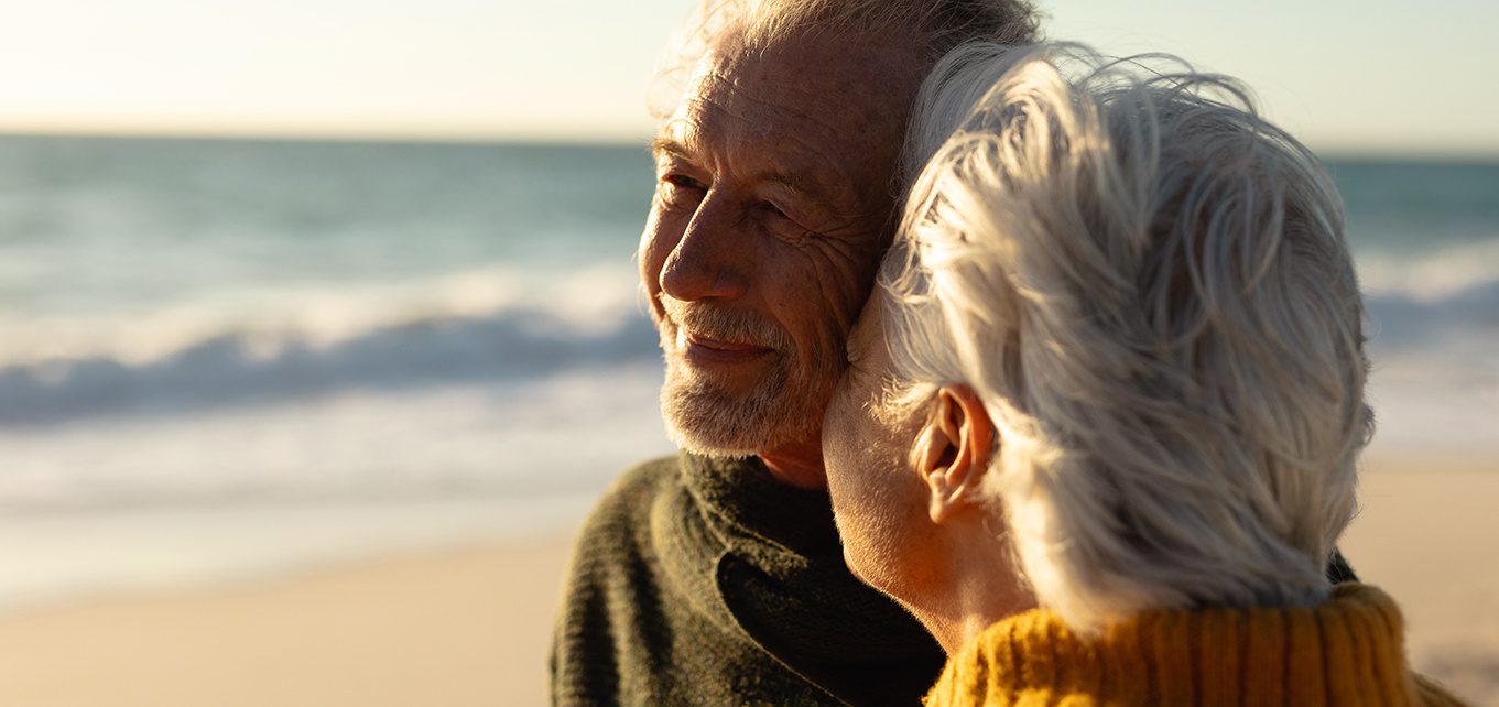 an older man and young woman on the beach