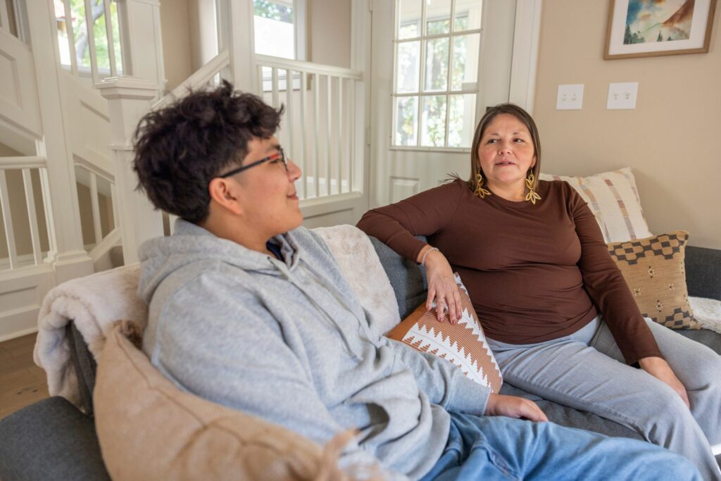 Mother and teenage son sitting on a couch having a conversation