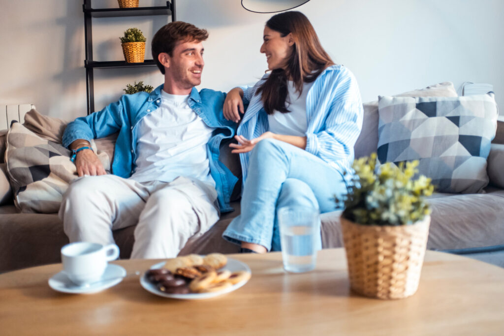 A couple sitting on a sofa at home, talking with each other
